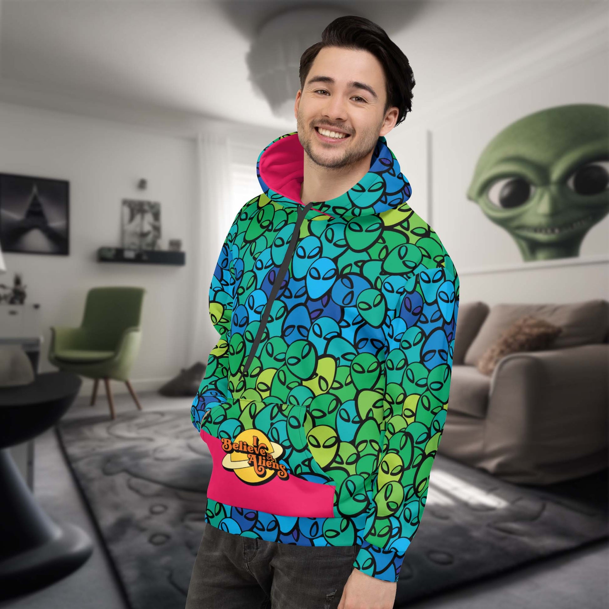 This Alien hoodie is printed all over with aliens. The inside of the hood is bright pink and so is a part of the front pocket. The front pocket has the meme: I believe in Aliens shown on it.
